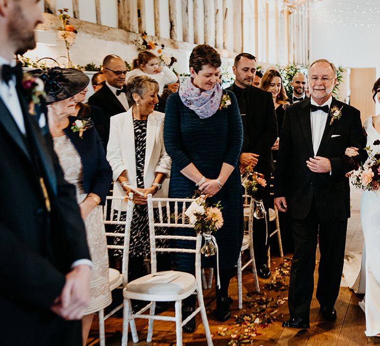 Bride walking down the aisle with the father of the bride at black tie wedding 