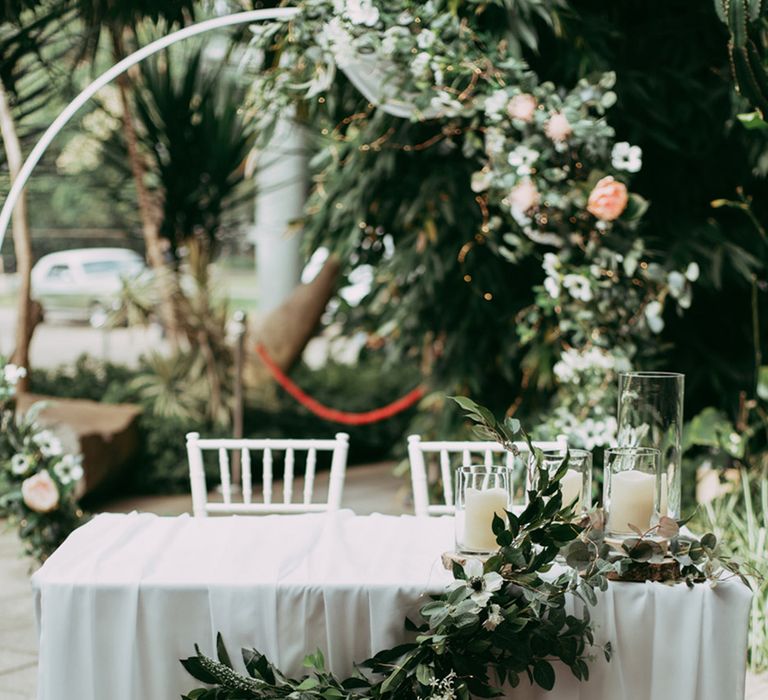 Sweetheart table with white table cloth and white wedding flower arrangement at wedding ceremony 