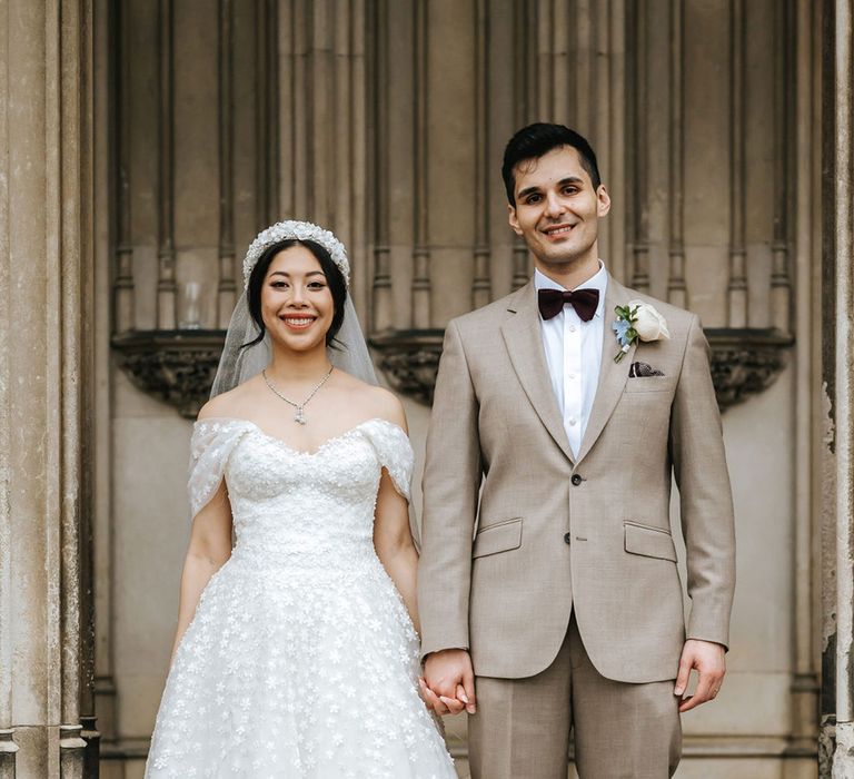 Bride wearing off the shoulder wedding dress with groom in beige suit for classic wedding 