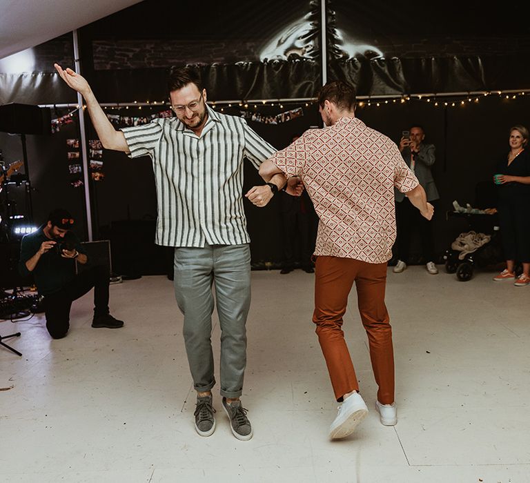 Two grooms in striped shirts having their first dance together 