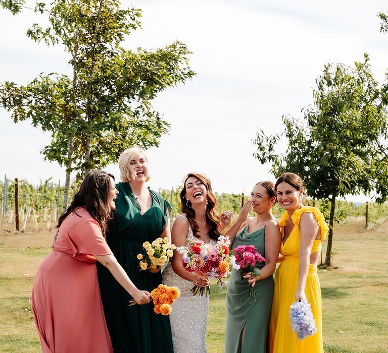 Bridesmaids wearing pink, yellow and green mismatched bridesmaid dresses for bridal party photo 