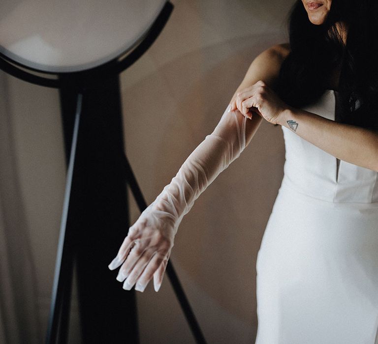 Bride putting on sheer bridal gloves accessory 