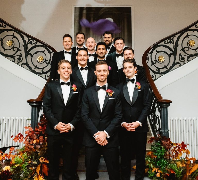 Groomsmen in black tuxedos gather on the stairs at Carlton House Terrace wedding 