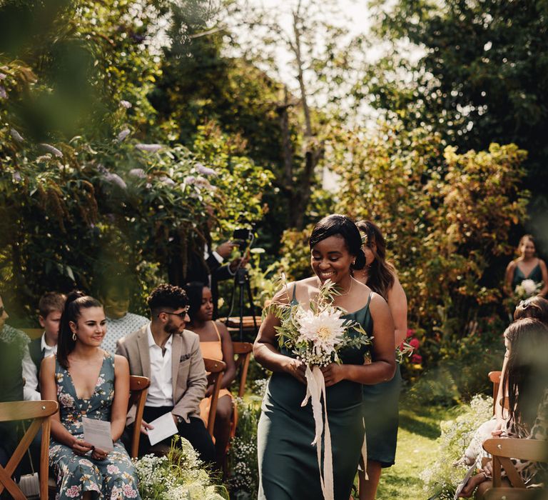 Bridesmaids in forest green satin dresses walking down the aisle 