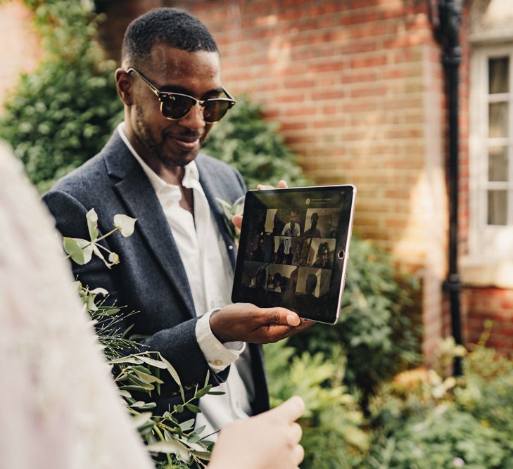 Bride and groom talking to guests virtually via a tablet 