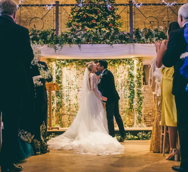 Bride and groom kissing at the altar with a fairy light back drop