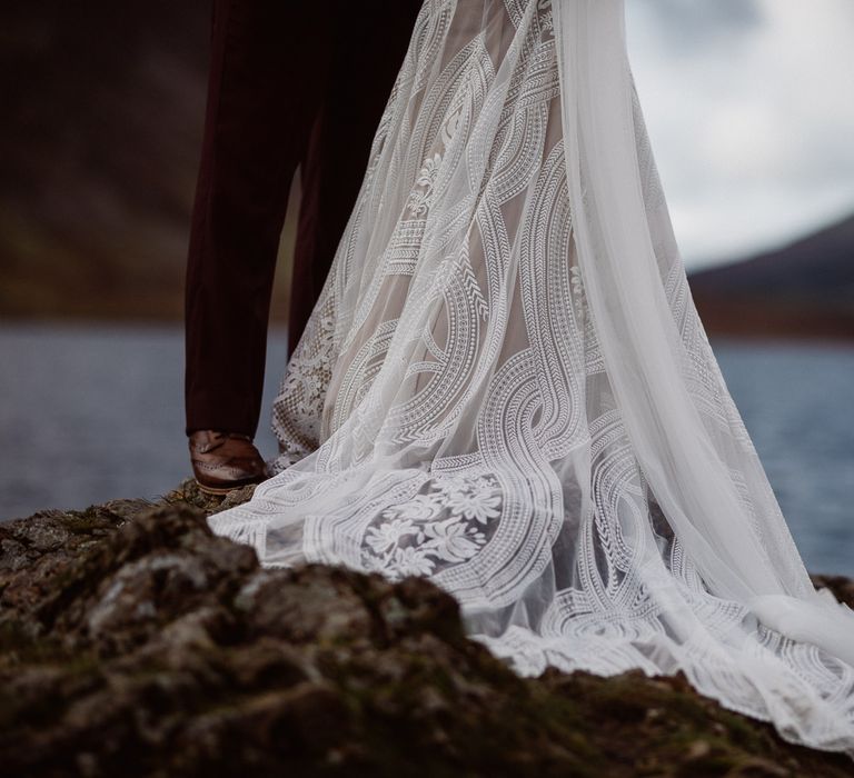 Details of boho wedding dress train by lake