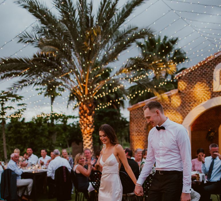 Bride and groom walk onto the outdoor dance floor hand in hand