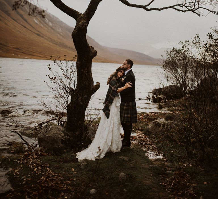 Bride and Groom pose by the loch at highland wedding in Glencoe