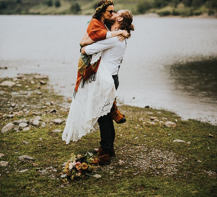 Groom picks up bride outside lakes