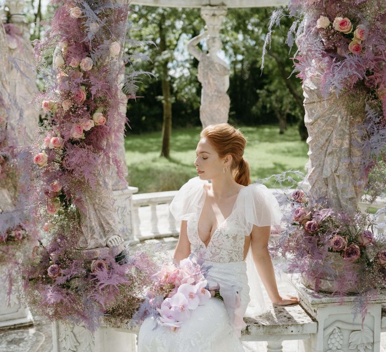 Bride looks away from the camera whilst sat down in the bandstand