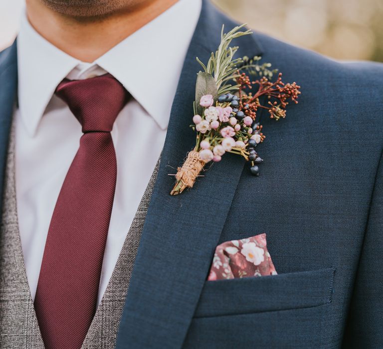 Groom wears colourful floral buttonhole tied with brown string