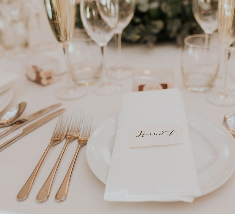 Rose gold cutlery, ink calligraphy place names and foliage centrepieces at stone barn Caswell House wedding