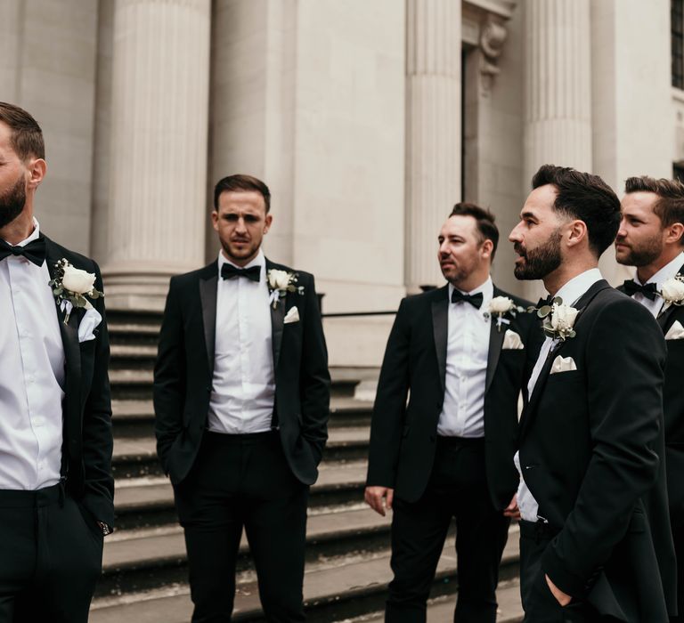 Groom stands with his groomsmen in black tie