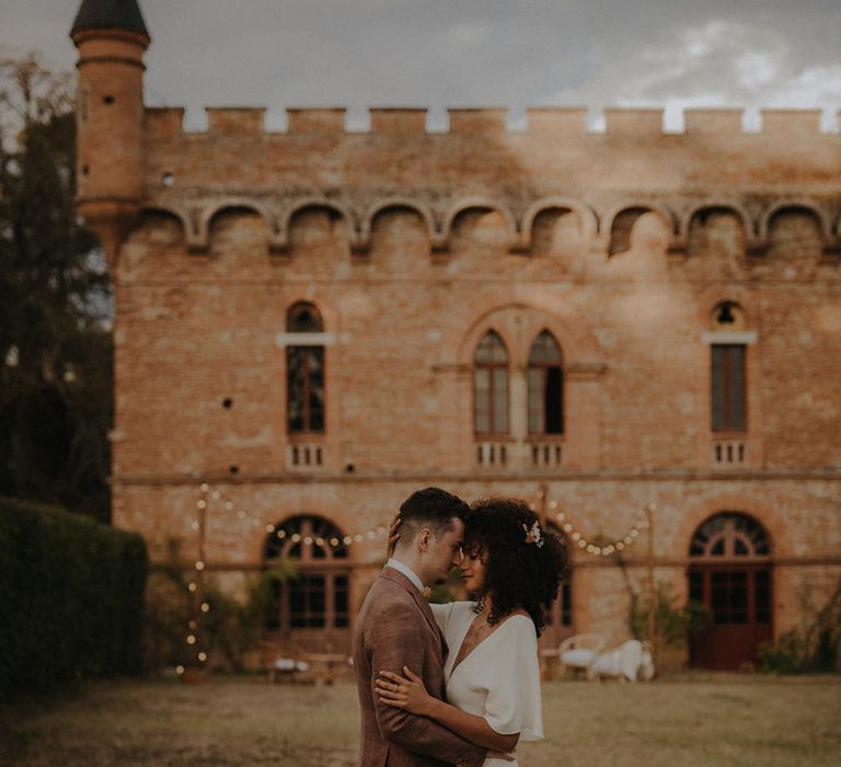 Bride and groom portrait outside a French Castle with festoon light decor 