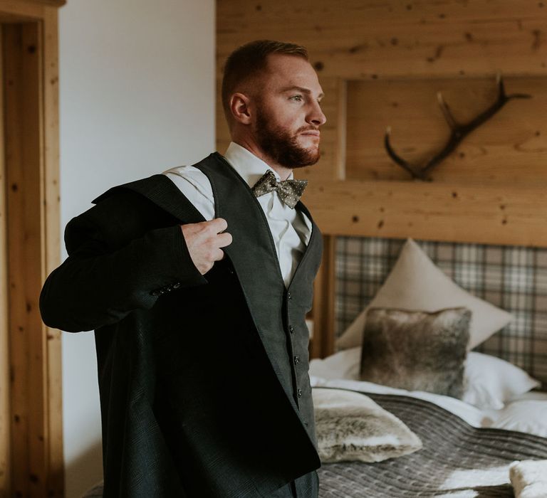 Groom on the wedding morning putting on his suit jacket 