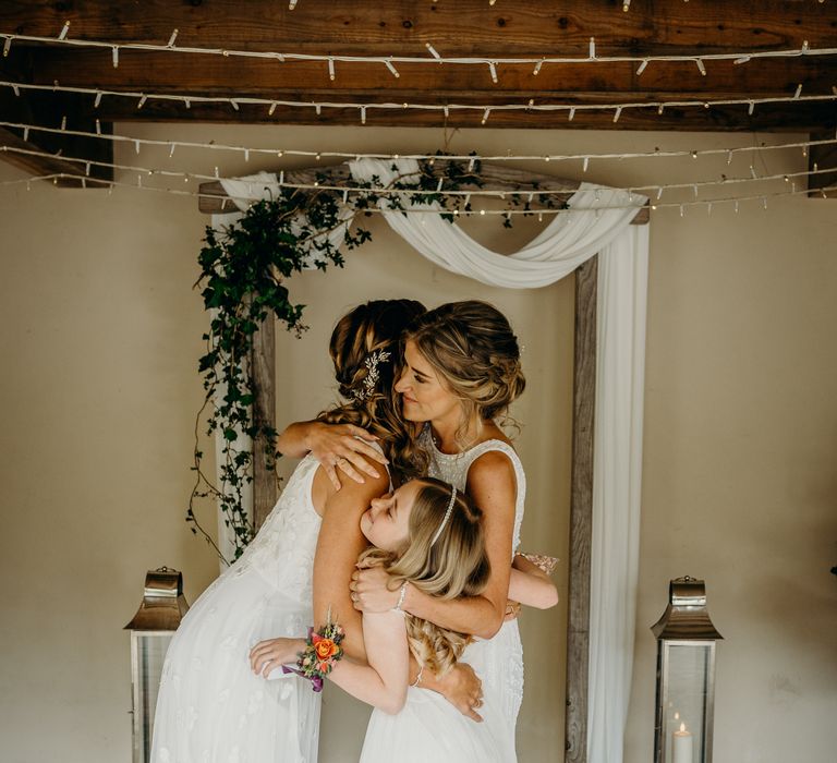 Brides embrace with daughter on their wedding day after ceremony