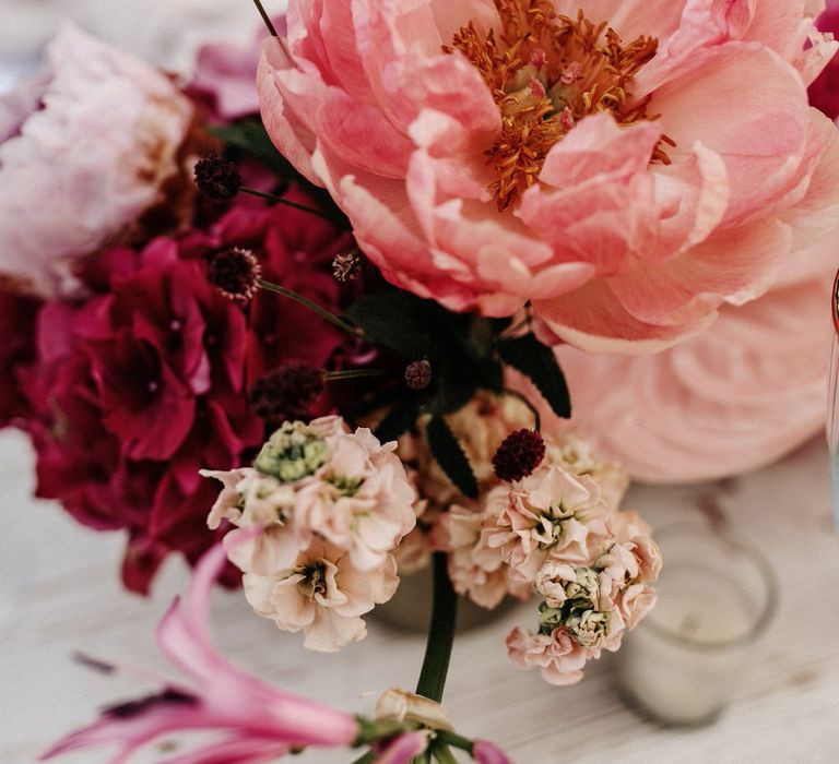 Floral centrepieces including pink peonies and hydrangea flowers for romantic finca wedding tablescape