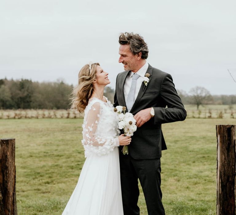 Bride and groom smiling at each other on the farm