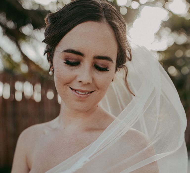 Bride looks down as she wears bronze eyeshadow and neutral makeup tones on her wedding day