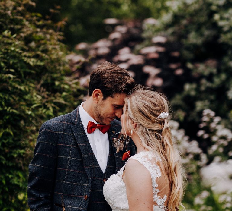 Bride & groom touch foreheads as she wears her blonde hair in loose curls with pearl hair accessory clip