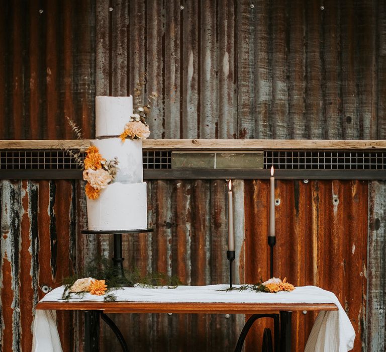 Three tier buttercream wedding cake resting on a black cake stand on a vintage Singer sowing machine table 