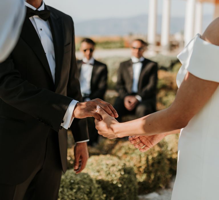 Groom places wedding ring on his brides finger during ceremony as wedding guests look on  | Hannah MacGregor Photo & Film