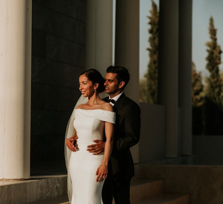 Groom wraps his arms around his bride on their wedding day in Amanzoe Greece Villa | Hannah MacGregor Photo & Film