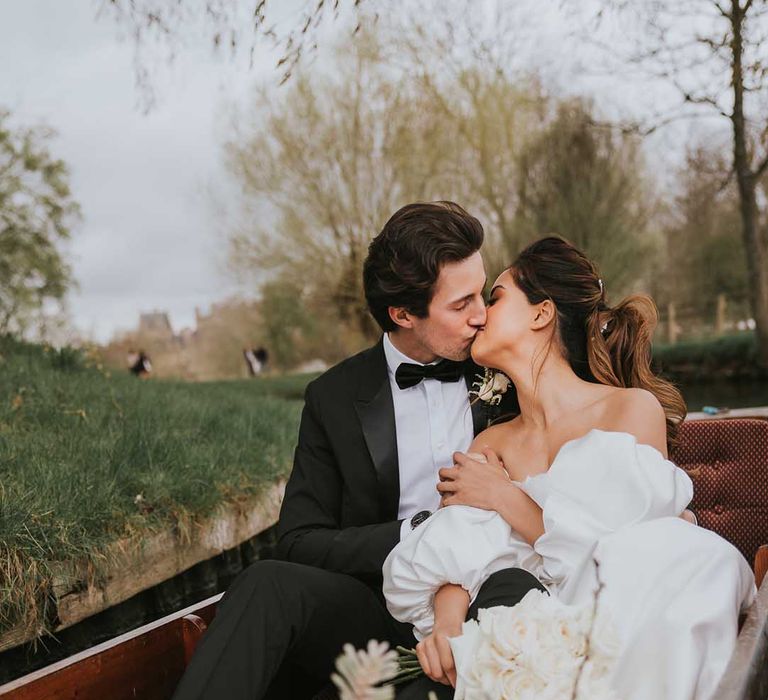 Bride and groom kissing in a boat at their Oxford wedding 