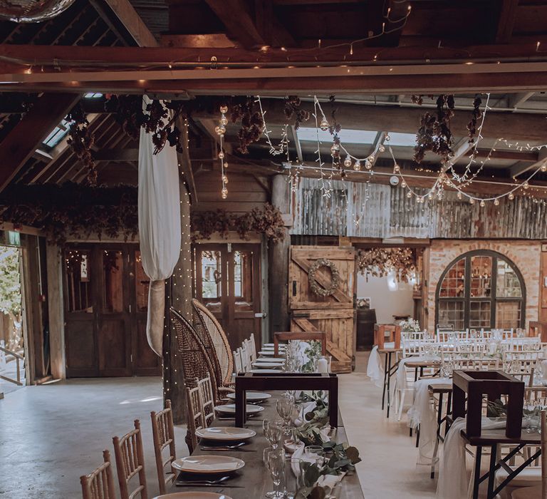 Rustic reception barn complete with white florals and wooden chairs