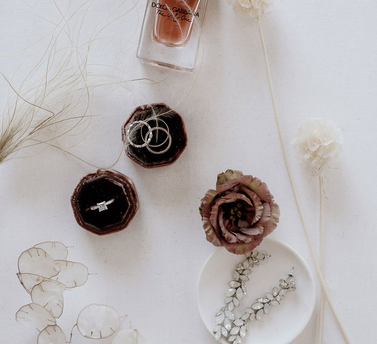 Bride & grooms wedding rings sit in black velvet box next to perfume and jewellery 