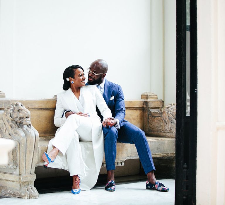 Bride & groom sit on sofa on their wedding day 