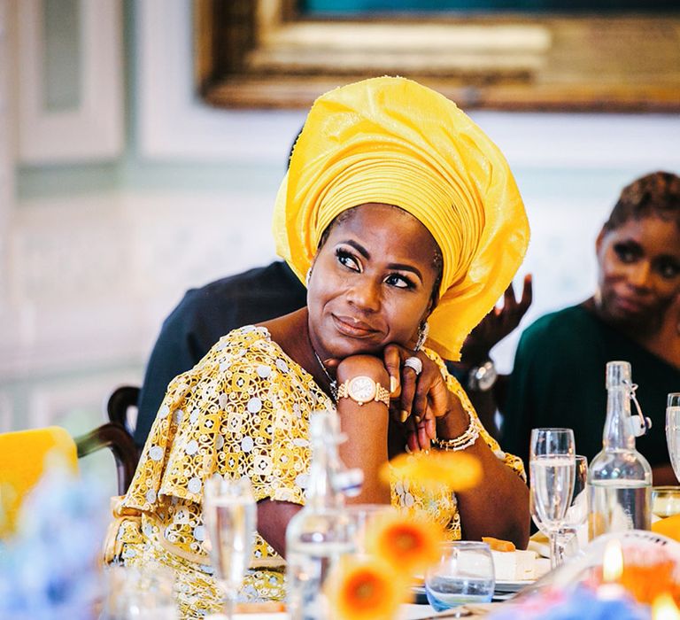 Wedding guest wears yellow traditional African outfit during wedding reception