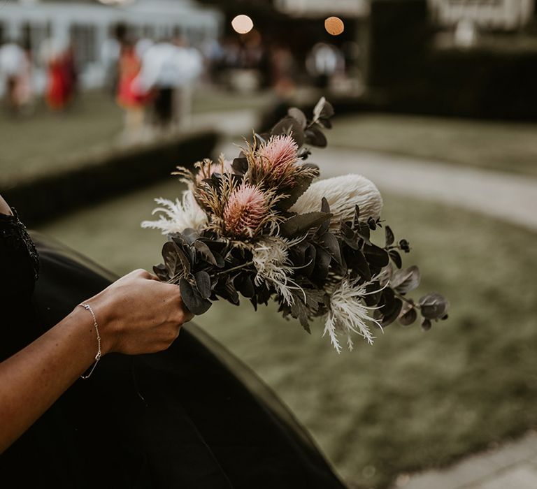 Bride holds pink and white floral bouquet complete with green foliage