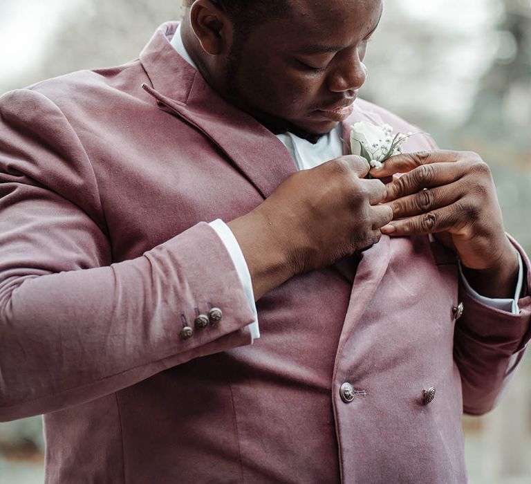 Groom applies floral buttonhole on his wedding day