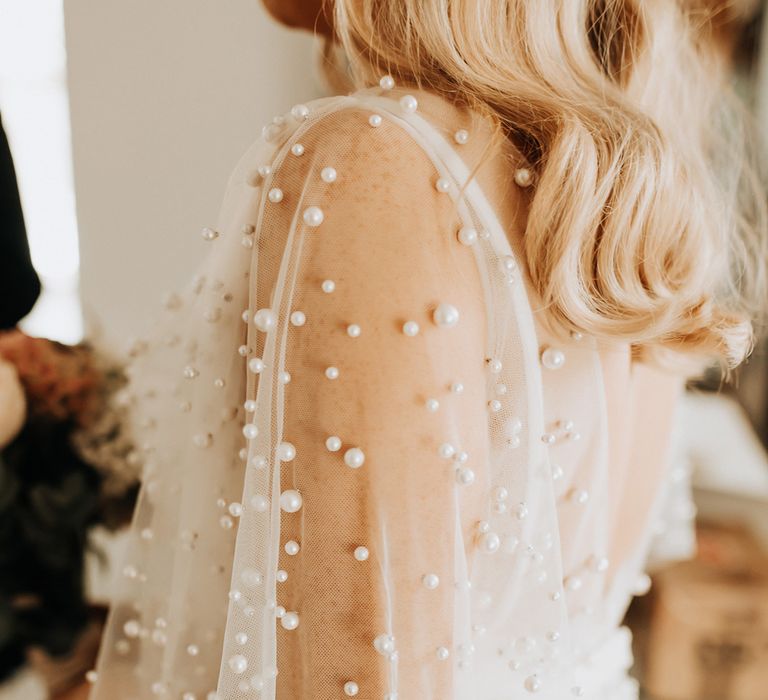 Bride in white wedding dress with mesh pearl encrusted sleeves 