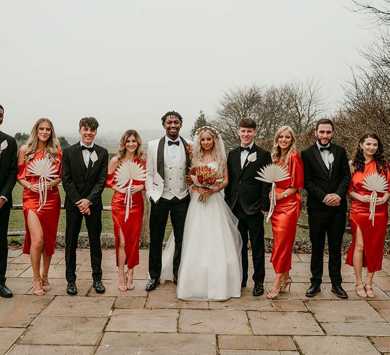 Black tie wedding with tuxedos and orange bridesmaid dresses