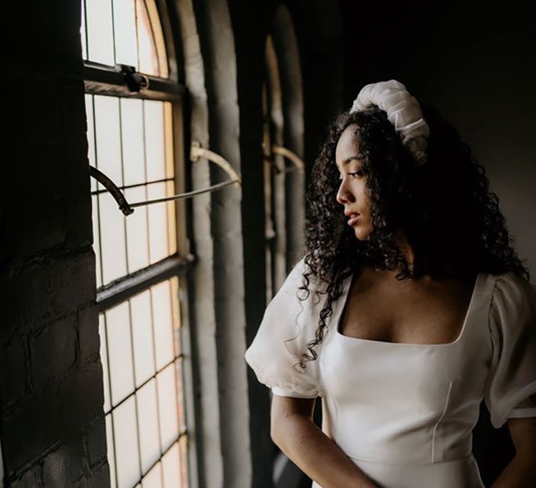 Black bride with long curly hair and a fabric headband wearing a square neckline STory Of My Dress wedding dress 