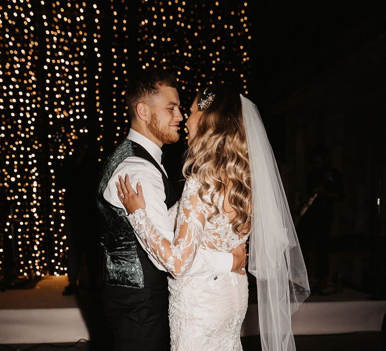 bride and groom share their first dance with groom in paisley waistcoat and bride in ruched lace wedding dress 