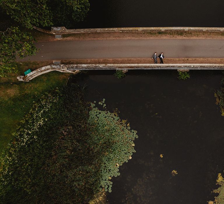 Grooms in different coloured suits lay on a bridge together