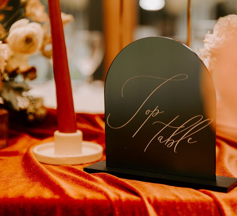 Arch shaped table sign with gold cursive font reading 'Top Table' 