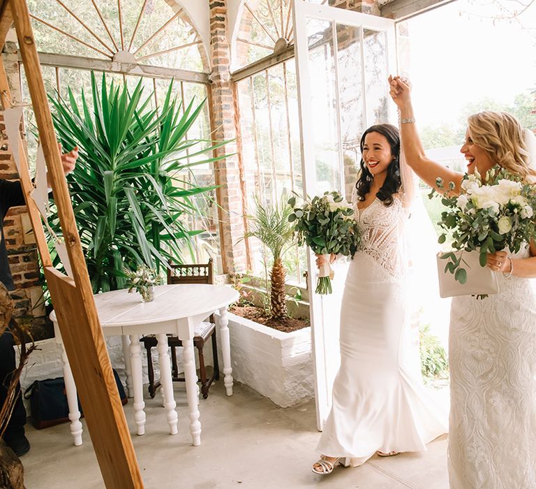 Brides walk into their wedding reception together holding hands 