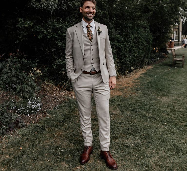 Groom in a stone coloured three-piece suit with paisley tie 