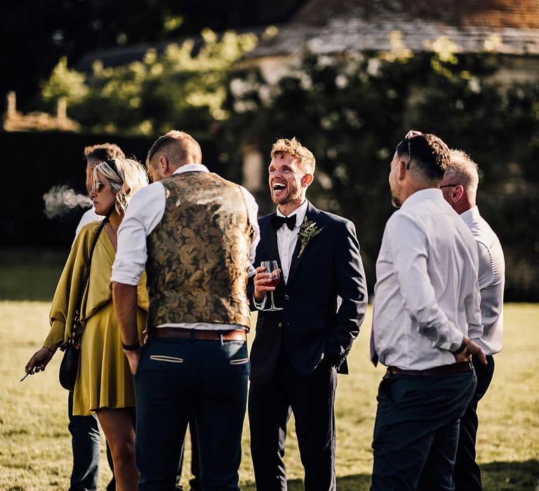 Groom laughs and socialises with the wedding guests for his outdoor wedding 