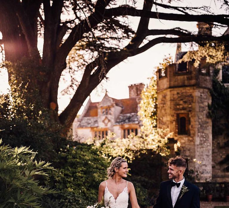 Bride and groom hold hands walking outside of their historic wedding venue 