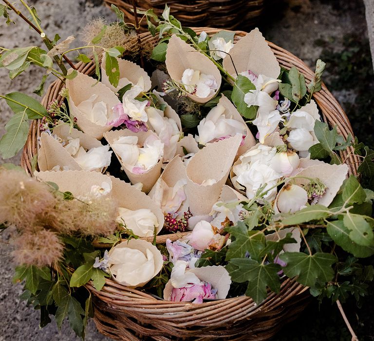 Petal confetti in paper cones in wicker baskets surrounded by florals 