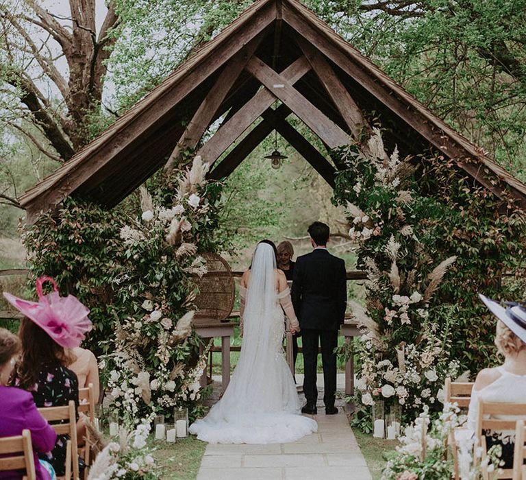 Bride and groom stand at the altar of their outdoor wedding at Millbridge Court wedding venue 