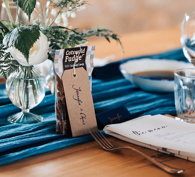 Blue table runner and white flower decor for table settings with fudge wedding favours 