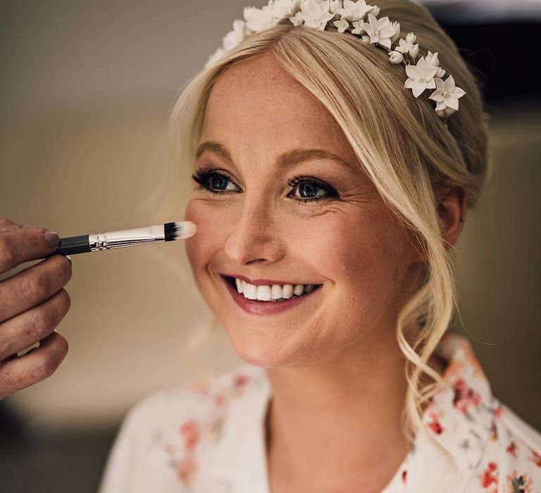 Bride in floral pyjamas gets her wedding makeup done for her traditional wedding church ceremony 