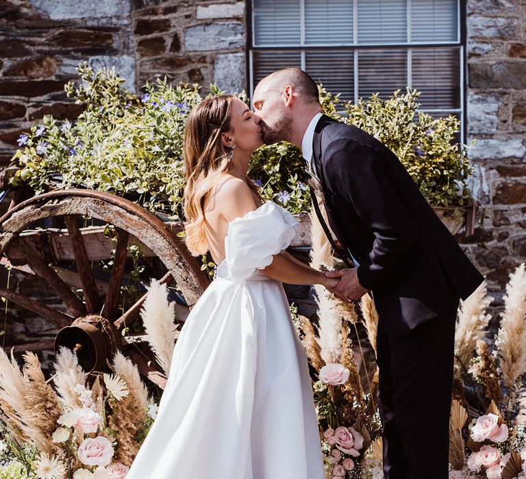 Bride and groom share their first kiss as a married couple at their outdoor wedding ceremony 